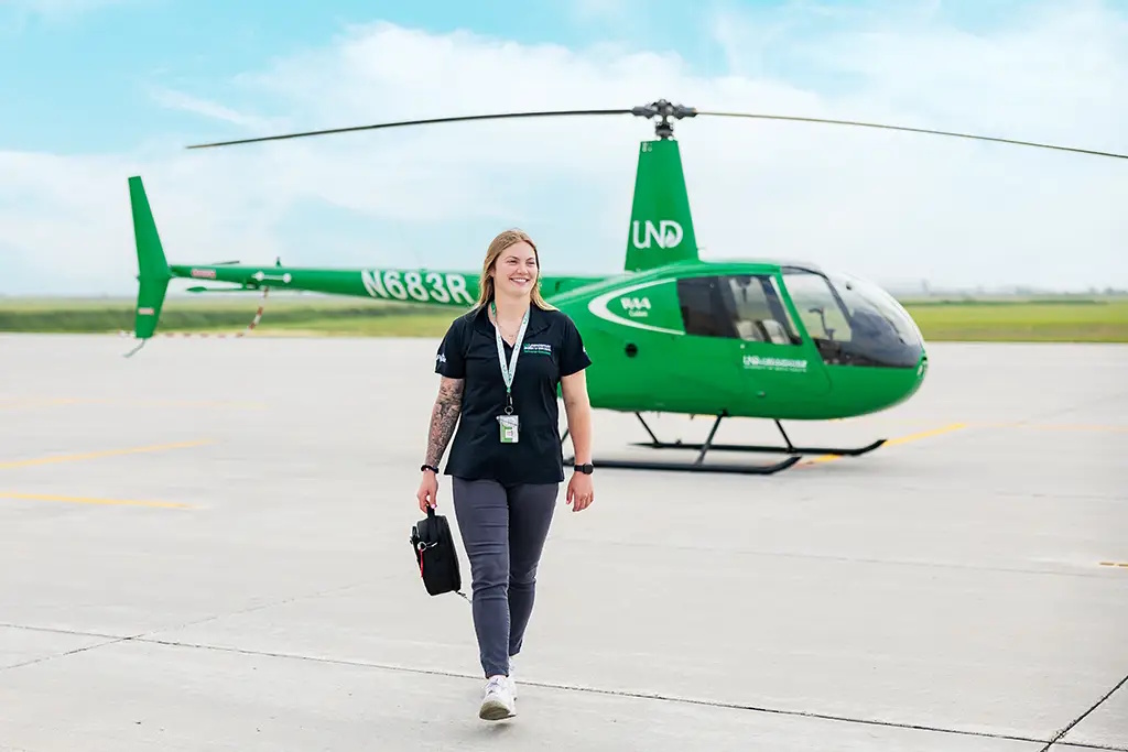 Ali Moses walks away from a green UND-branded helicopter