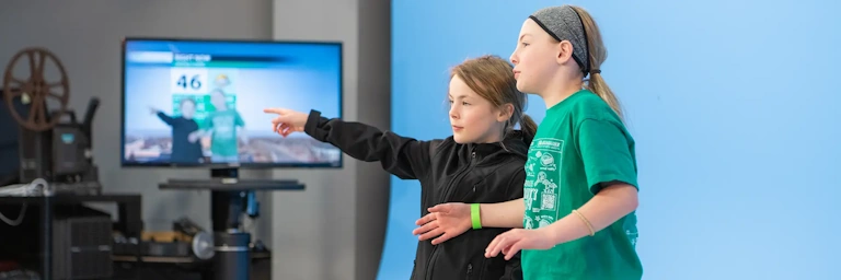 UND Aerospace Community Day attendees pretend to be meteorologists in front of a blue screen