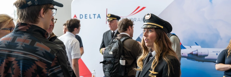 Student speaks with recruiter at a career fair in an airport hangar