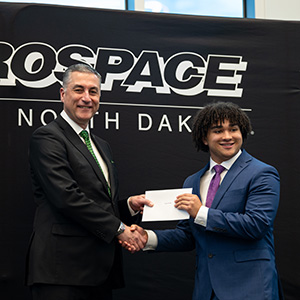 A scholarship recipient shakes hands with the Dean